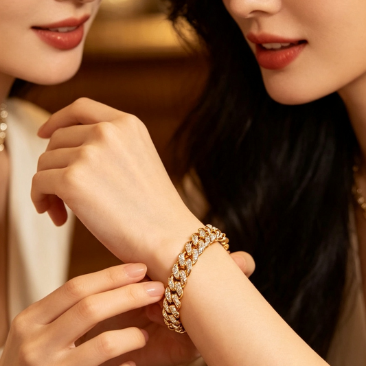 A close-up lifestyle shot of a woman wearing a gold chain bracelet, with another woman looking on in a warm, elegant indoor setting.